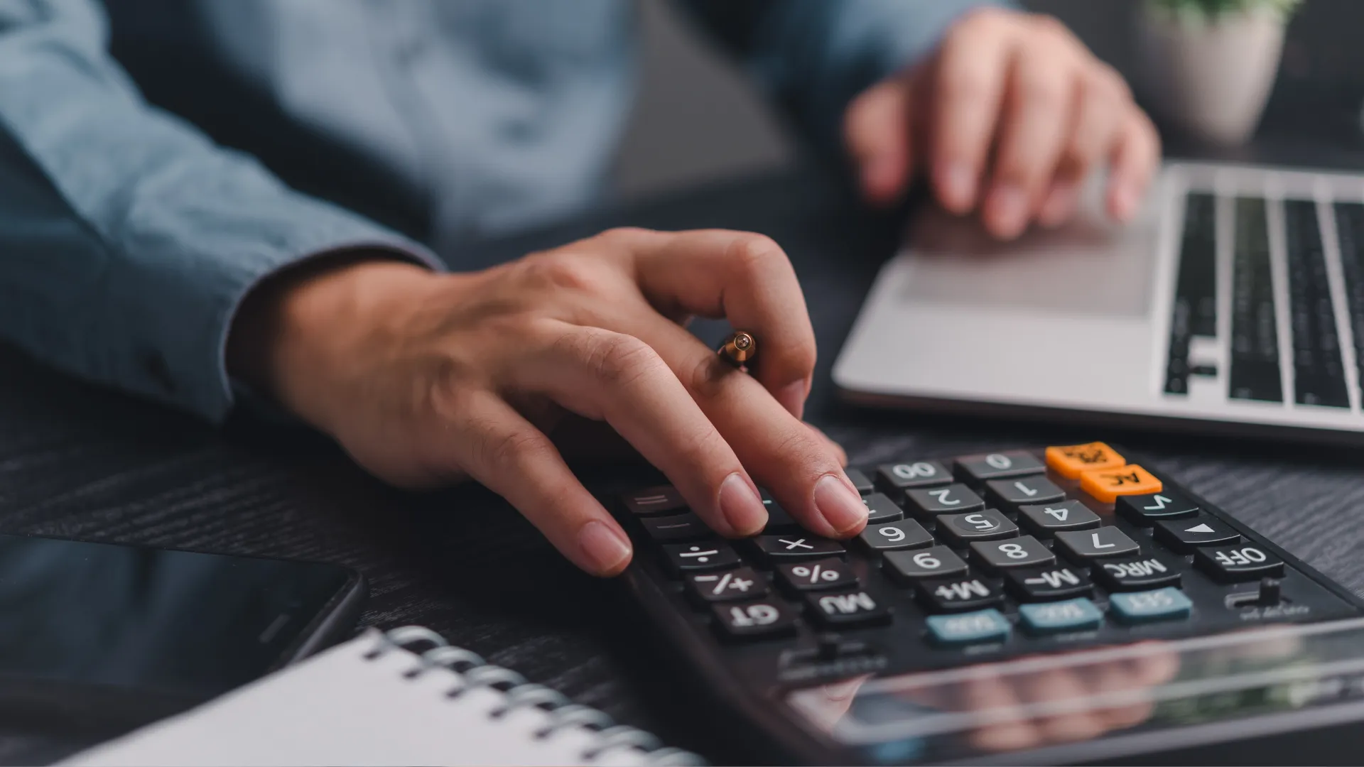 Small business accounting Calgary professional calculating numbers on a laptop with a calculator