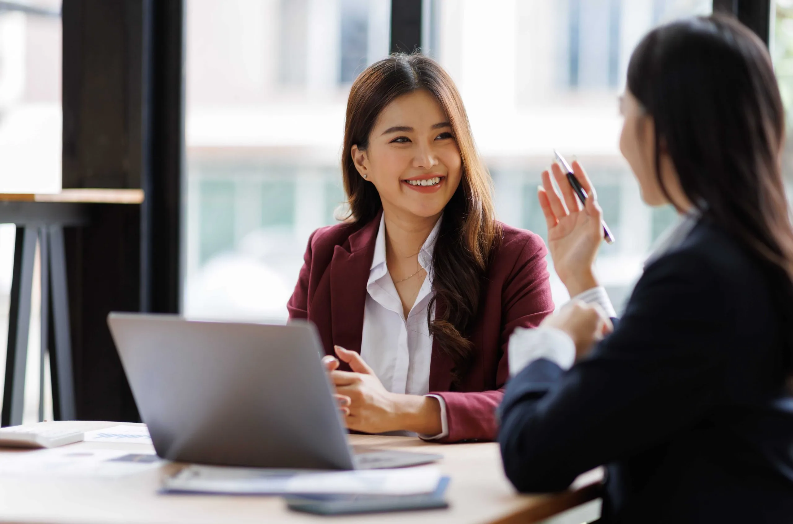 Two women discussing fractional CFO services and bookkeeping strategies at a table with a laptop