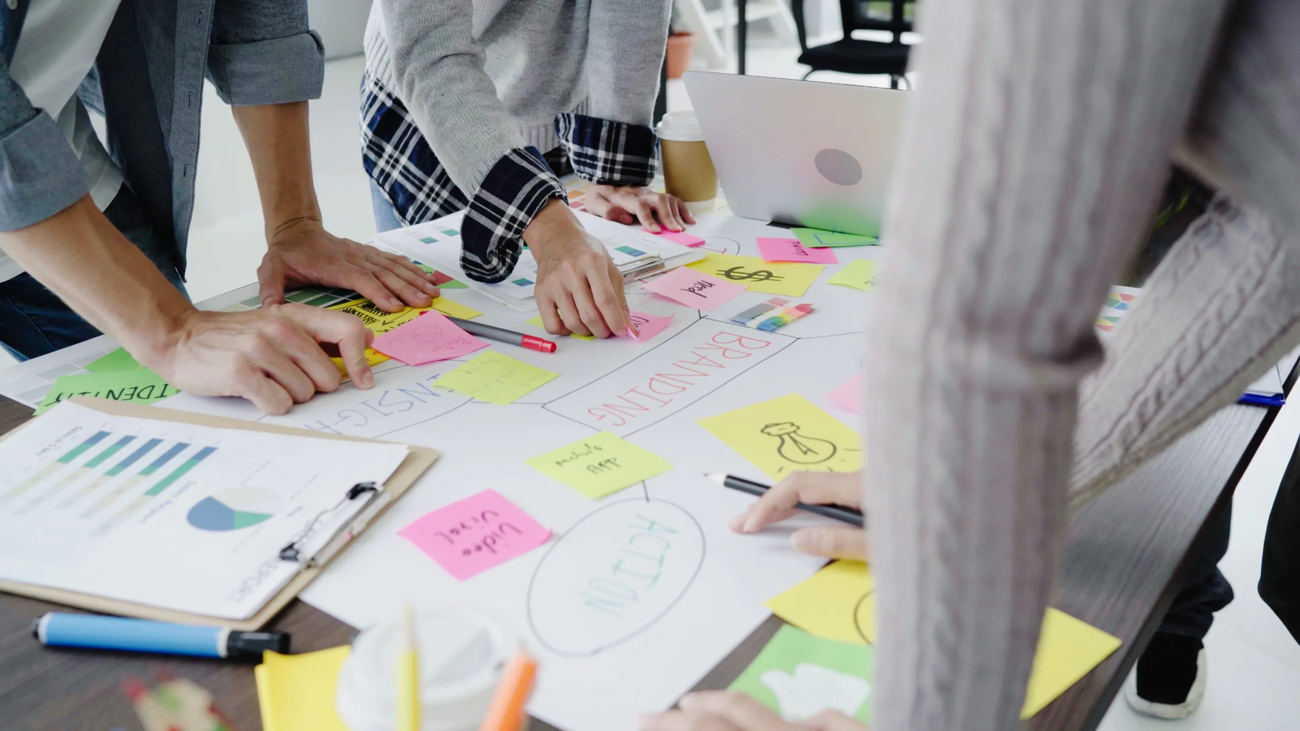 People collaborate around a table covered with colorful sticky notes and documents